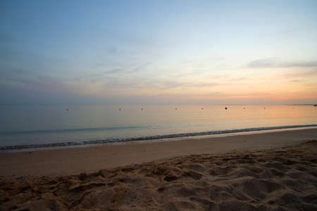 Calm sea shore with crushing waves on sandy beach at sunrise.