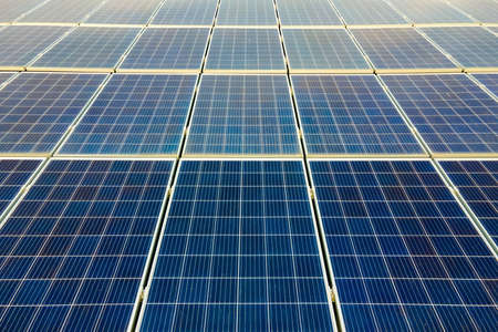 Aerial view of surface of blue photovoltaic solar panels mounted on building roof for producing clean ecological electricity. Production of renewable energy concept.の写真素材