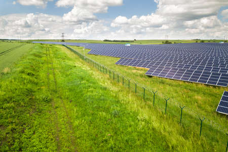 Aerial view of solar power plant on green field. Electric panels for producing clean ecologic...