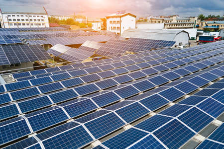 Aerial view of blue photovoltaic solar panels mounted on industrial building roof for producing green ecological electricity. Production of sustainable energy concept.の写真素材