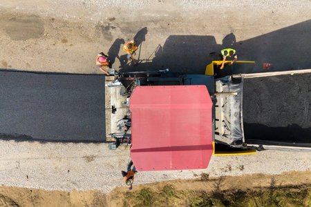 Aerial view of new road construction with asphalt laying machinery at work.