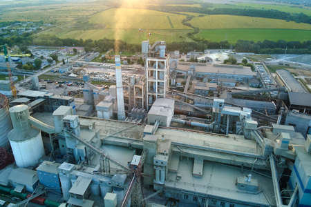 Aerial view of cement factory with high concrete plant structure and tower crane at industrial production site. Manufacture and global industry concept.の写真素材