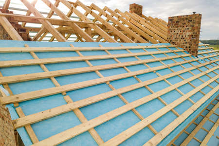 Aerial view of a brick house with wooden roof frame under construction.の写真素材