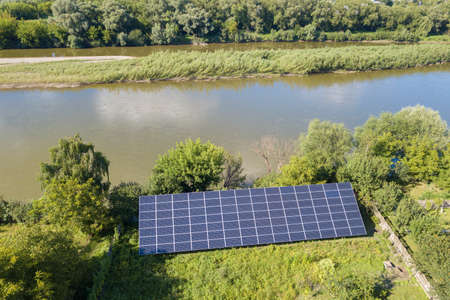 Aerial view of blue photovoltaic solar panels mounted on backyard ground for producing clean...