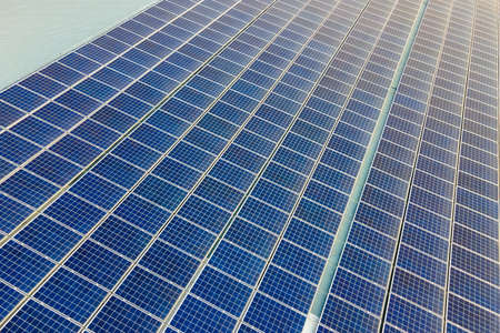 Aerial view of surface of blue photovoltaic solar panels mounted on building roof for producing...