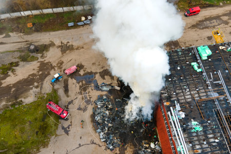 Aerial view of firefighters extinguishing fire in industrial area.の写真素材