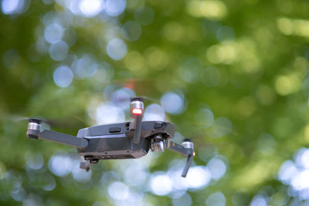 Drone copter with blurred propellers and video camera flying in air.