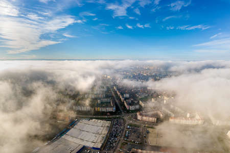 Top aerial view of fluffy white clouds over modern city with high rise buildings.の写真素材