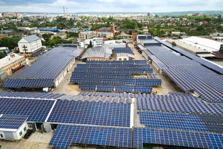 Aerial view of solar power plant with blue photovoltaic panels mounted on industrial building roof for producing green ecological electricity. Production of sustainable energy concept.の写真素材