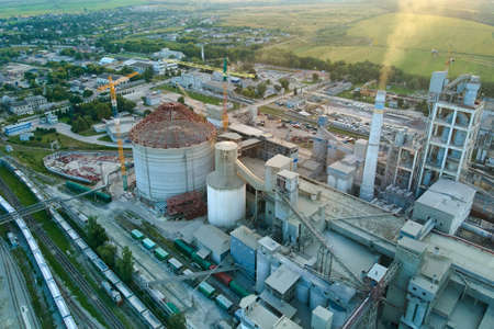 Aerial view of cement factory with high concrete plant structure and tower crane at industrial production site. Manufacture and global industry concept.の写真素材