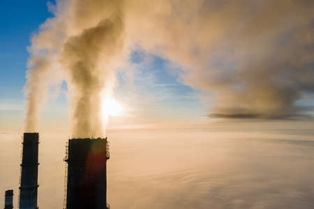 Aerial view of coal power plant high pipes with black smoke moving up polluting atmosphere at sunset.の写真素材