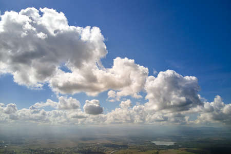 Aerial view from airplane window at high altitude of earth covered with white puffy cumulus clouds.の写真素材