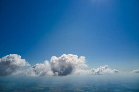 Aerial view from airplane window at high altitude of earth covered with white puffy cumulus clouds.の写真素材