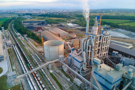 Aerial view of cement factory with high concrete plant structure and tower crane at industrial production site. Manufacture and global industry concept.のeditorial素材
