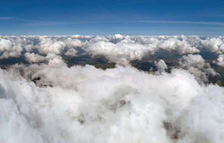 Aerial view from airplane window at high altitude of earth covered with puffy cumulus clouds forming before rainstormの写真素材