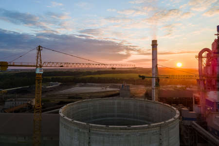 Aerial view of cement factory under construction with high concrete plant structure and tower cranes...