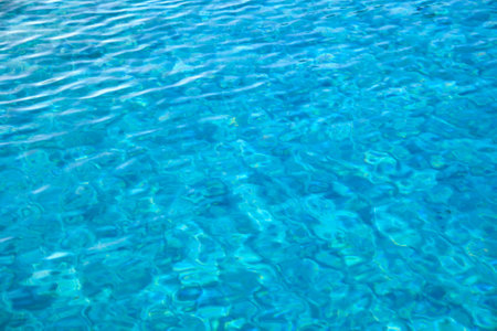 Closeup surface of blue clear water with small ripple waves in swimming pool.