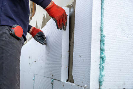 Construction worker installing insulation sheets on house facade wall for thermal protectionの写真素材