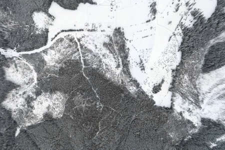 Top down aerial view of snow covered evergreen pine forest after heavy snowfall in winter mountain...