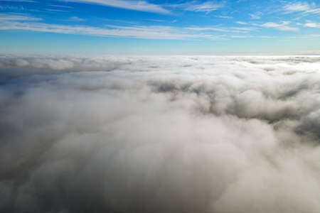 Aerial view from above of white puffy clouds in bright sunny dayの写真素材