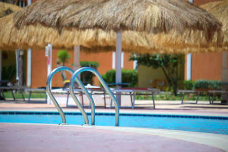 Close up of swimming pool stainless steel handrail descending into tortoise clear pool water....