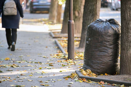 Pile of black garbage bags full of litter left for pick up on street side. Trash disposal conceptの写真素材
