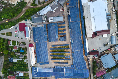 Aerial view of blue photovoltaic solar panels mounted on industrial building roof for producing...