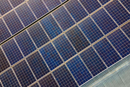 Closeup of surface of blue photovoltaic solar panels mounted on building roof for producing clean...