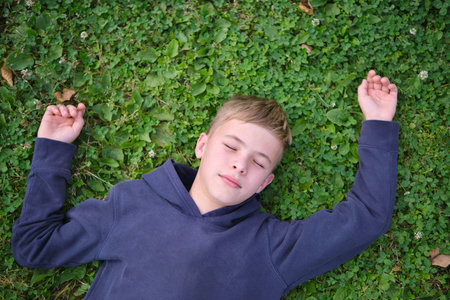 Portrait of child boy outdoors resting on grass lawn.の写真素材