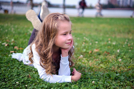 Portrait of pretty child girl outdoors lying down on grass lawn.の写真素材