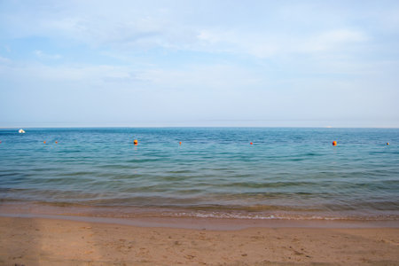Seascape with surface of blue sea water with small ripple waves crashing on yellow sandy beach. Travel and vacations concept.の写真素材