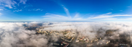 Top aerial view of fluffy white clouds over modern city with high rise buildings.の写真素材