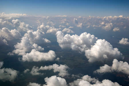 Aerial view from airplane window of white puffy clouds on bright sunny day