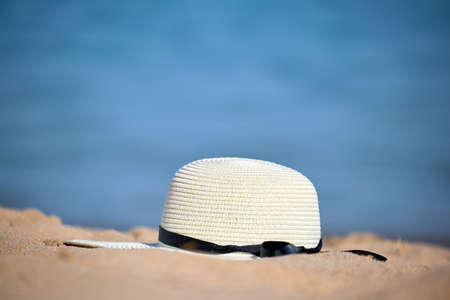 Closeup of yellow straw hat on sandy beach at tropical seaside on warm sunny day. Summer vacation conceptの写真素材