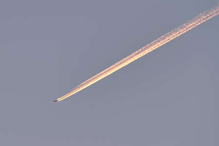Distant passenger jet plane flying on high altitude on clear blue sky leaving white smoke trace of contrail behind. Air transportation conceptの写真素材