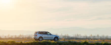 SUV car driving fast on intercity road at sunset. Highway traffic in eveningの写真素材