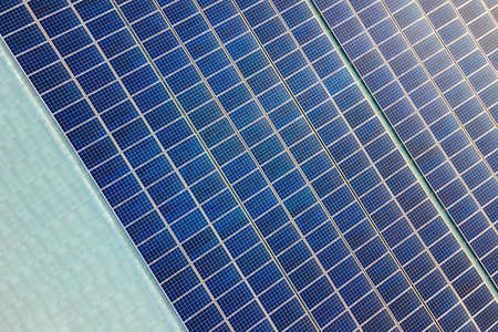 Closeup of surface of blue photovoltaic solar panels mounted on building roof for producing clean...