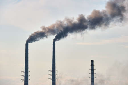 Coal power plant high pipes with black smoke moving upwards polluting atmosphere. Production of...