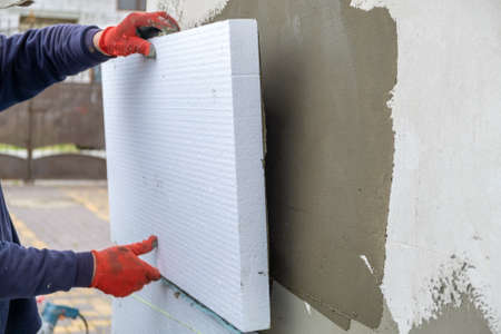 Construction worker installing styrofoam insulation sheets on house facade wall for thermal protectionの写真素材