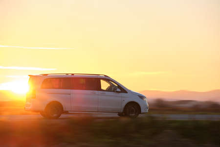 Passenger van driving fast on intercity road at sunset. Highway traffic in eveningの写真素材