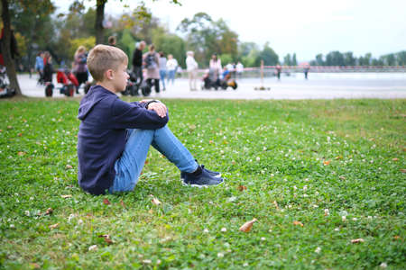 Portrait of child boy outdoors resting on grass lawnの写真素材