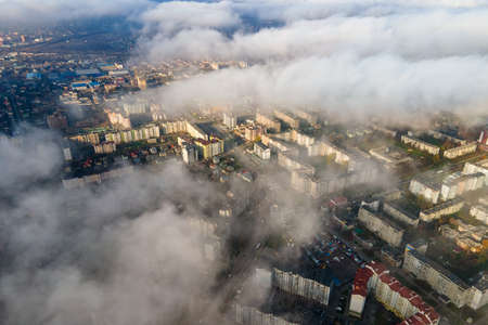 Top aerial view of fluffy white clouds over modern city with high rise buildings