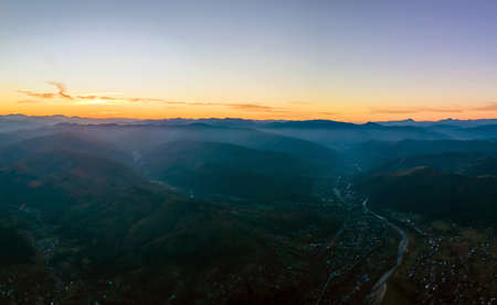 Aerial view of dark mountain hills at sunset. Hazy peaks and misty valleys in eveningの写真素材