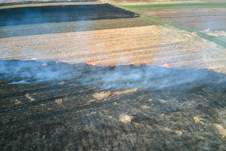 Aerial view of grassland field burning with red fire during dry season. Natural disaster and climate...