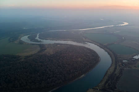 Aerial view of wide river flowing quietly in rural countryside in autumn eveningの写真素材