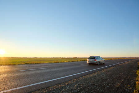 Car driving fast on intercity road at sunset. Highway traffic in evening