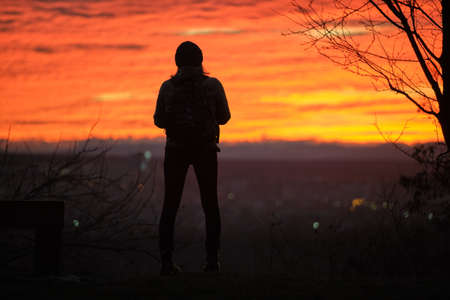 Dark silhouette of a lonely woman enjoying sunset view in evening nature. Loneliness and solitude...