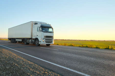 Semi-truck with cargo trailer driving on highway hauling goods in evening. Delivery transportation...