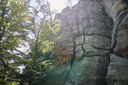 Young child boy climbing steep wall of rocky mountain. Kid climber overcomes challenging route....