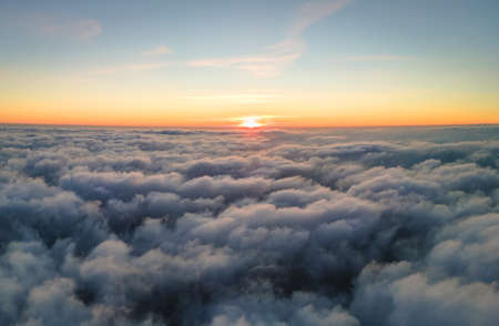 Aerial view from airplane window at high altitude of dense puffy cumulus clouds flying in evening